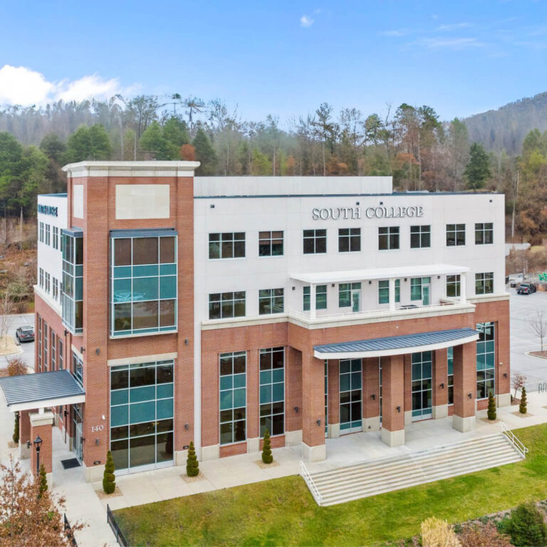 A four-story building with "South College" written on the front. The structure features a combination of brick and white facade with large blue-tinted windows.