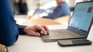 A person uses a laptop computer on a desk.