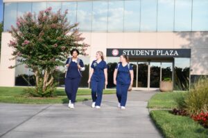 3 Nursing students walking in front of South College Student Plaza outside of Parkside campus.