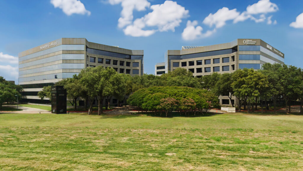 A wide-angle view of two modern multi-story office buildings set amid lush green lawns and trees.